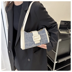 Détail du sac à bandoulière en denim et cuir porté avec un blazer noir professionnel