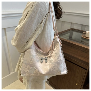 Detail of pink brocade tote with traditional landscape patterns and silver bow decoration