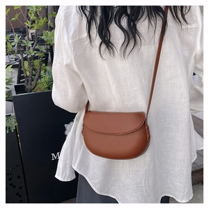 Detail shot of a brown saddle bag featuring smooth matte finish and a rivet adjustment buckle