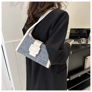 Détail du sac baguette en denim bleu avec bordure en cuir blanc et boucle carrée