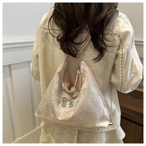 Rear view of a model wearing a pink oriental jacquard tote with silver bow and chain strap