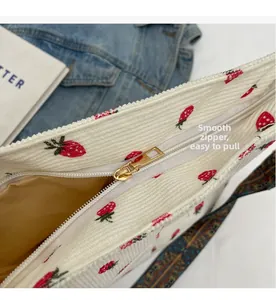 Detail of smooth gold zipper on corduroy strawberry bag with colorful woven strap