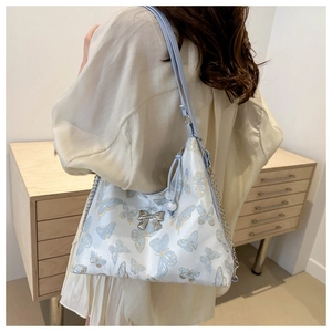Detail of light blue tote bag with butterfly embroidery and silver bow fastener