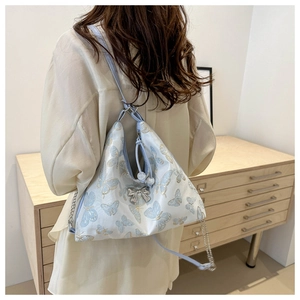 Detail of light blue tote bag with butterfly embroidery and silver bow pendant