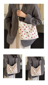 Close-up of white corduroy tote bag with strawberry print and colorful woven shoulder strap