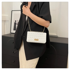 Sac bandoulière blanc matelassé avec chaîne dorée porté par un mannequin femme