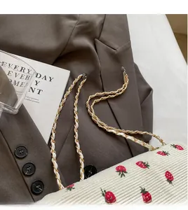 Detail of strawberry corduroy tote bag with woven gold chain strap on a brown blazer