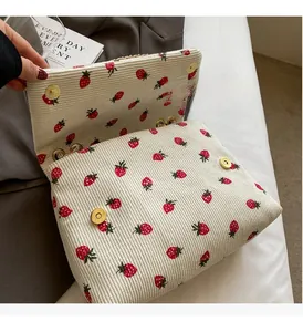 Detail of white corduroy bag with strawberry print and gold magnetic closures