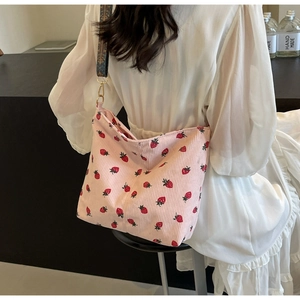 Pink corduroy crossbody bag with strawberry pattern and ethnic style woven strap detail
