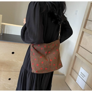 Detail of brown corduroy bucket bag with red strawberry print and golden buckle