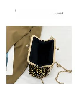 Macro detail of black evening bag with gold sequins, metal clasp and pearl chain strap
