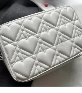 Close-up of white heart-quilted crossbody bag showing soft synthetic leather texture