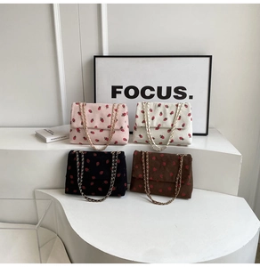 Detail of four corduroy floral bags with strawberry embroidery and gold chain straps