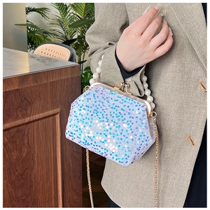 Detail of sequin evening bag with pearl handle and metal chain shown on a model