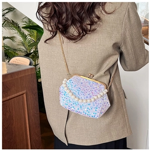 Detail of sequin clutch bag with pearl handle and golden chain on model attire