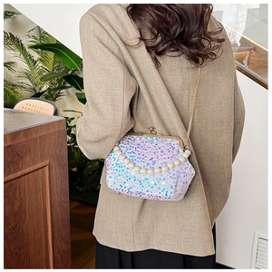 Detail of sequin shell bag with pearl handle and metal chain on a model