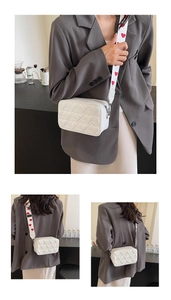 Detailed view of a white camera bag featuring heart quilting and a red heart strap
