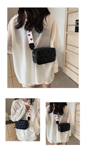 Detail of heart quilted black crossbody bag with red and white heart pattern strap