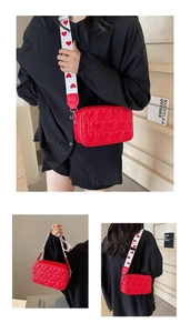 Detail of red heart-quilted crossbody bag with unique white heart-pattern wide strap