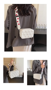 Detailed view of white quilted crossbody bag with red heart printed wide strap