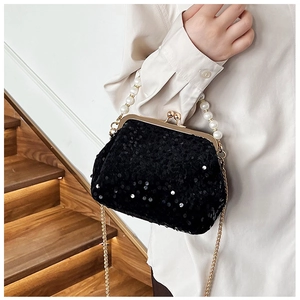 Close-up of black sequin evening bag with white pearl handle and gold chain strap