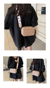 Detail of beige heart-quilted crossbody bag with red heart pattern wide fabric strap