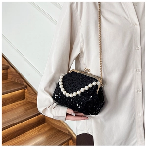 Close-up of black sequined evening bag featuring pearl handle and gold chain strap