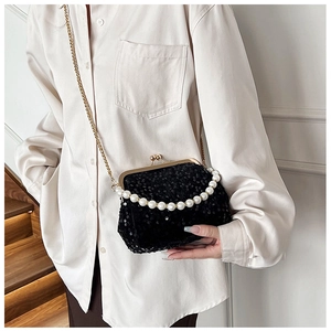 Detail of black sequined evening bag featuring large pearl handle and gold chain strap