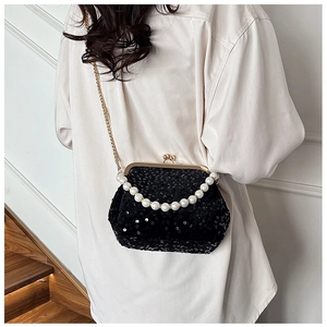 Close-up of black sequined clutch bag with pearl handle and gold metal frame