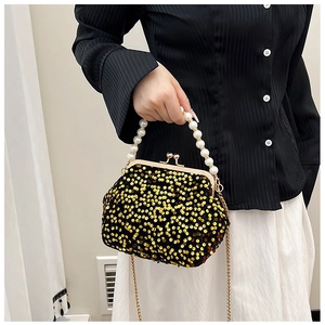 Elegant model carrying a sparkly sequin evening bag with a pearl handle and gold chain
