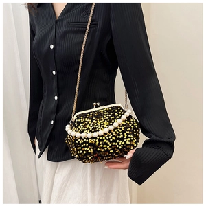Close-up of sparkling gold sequin evening bag with elegant pearl handle and metal chain