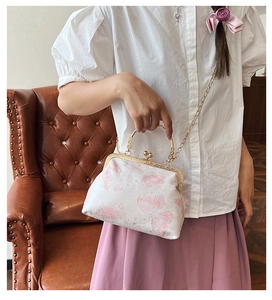 Dettaglio borsa vintage in raso bianco con farfalle rosa e tracolla a catena dorata