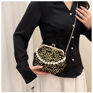 Macro detail of gold sequins and pearl handle chain on a black crossbody evening bag