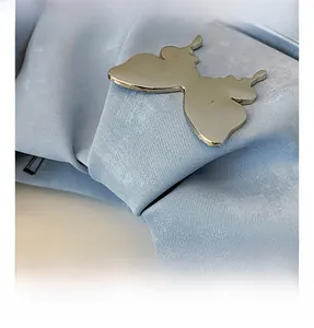 Macro shot of silver butterfly metal hardware on light blue textured shoulder bag