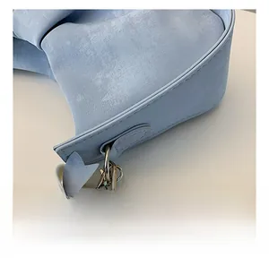 Macro view of blue pleated handbag featuring metal chain, pearls and bow decoration