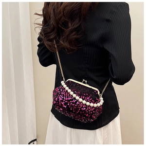 Detail of sequin evening clutch bag with pearl strap and gold chain worn crossbody