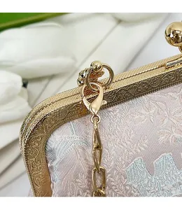 Dettaglio del tessuto jacquard floreale con cornice in metallo dorato e chiusura a moschettone