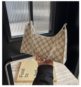 Vista dettagliata della borsa a mezzaluna con motivo a quadrifoglio su pelle beige