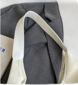 Détail de la poignée en cuir blanc montrant les coutures solides sur une veste grise