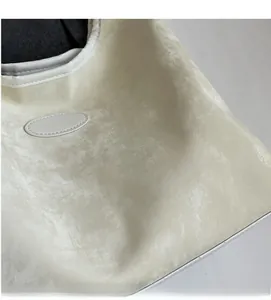 Gros plan sur le tissu en daim crème doux et la bordure en cuir blanc du sac cabas