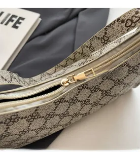 Dettaglio ravvicinato della cerniera dorata su una borsa a tracolla con stampa monogramma