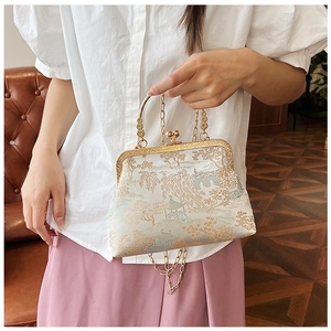 Dettaglio borsa in broccato bianco con ricamo di paesaggio e tracolla a catena d'oro