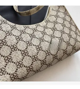 Dettaglio del tessuto beige testurizzato con motivo a quadrifoglio marrone e cuciture
