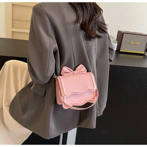 Detail of pink crossbody bag with a 3D bow on wavy flap and silver chain strap