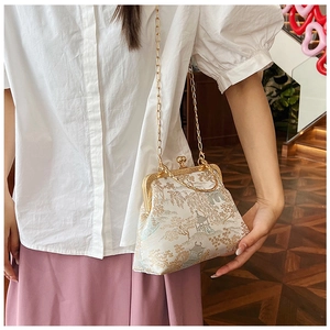 Dettaglio borsa vintage in jacquard con motivo tradizionale e catena in metallo dorato
