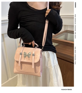 Pink matte crossbody bag with silver butterfly buckle detail and top handle shown on model
