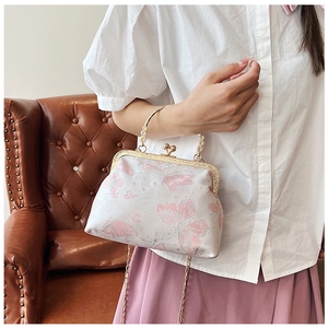 Dettaglio borsa vintage in broccato beige con ricamo a farfalla rosa e catena dorata