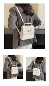 Detail of white pleated faux leather backpack featuring a silver butterfly buckle