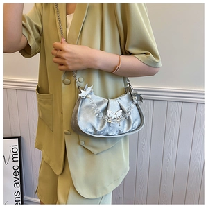 Detail of silver metallic pleated handbag featuring pearl bead handle and bow hardware