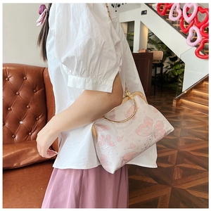 Dettaglio borsa stile qipao rosa con motivo a farfalla e manico tondo in metallo dorato